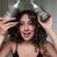 Woman with curly hair holding Act+Acre Shampoo + Conditioner