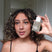 Woman with curly hair holding  Act+Acre Stem Cell Scalp Serum