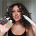 Woman with dark curly hair holding Act+Acre Scalp Relief System