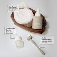 Skincare products for scalp care including a hair towel, travel scalp serum, and scalp dermastamp on a white background.
