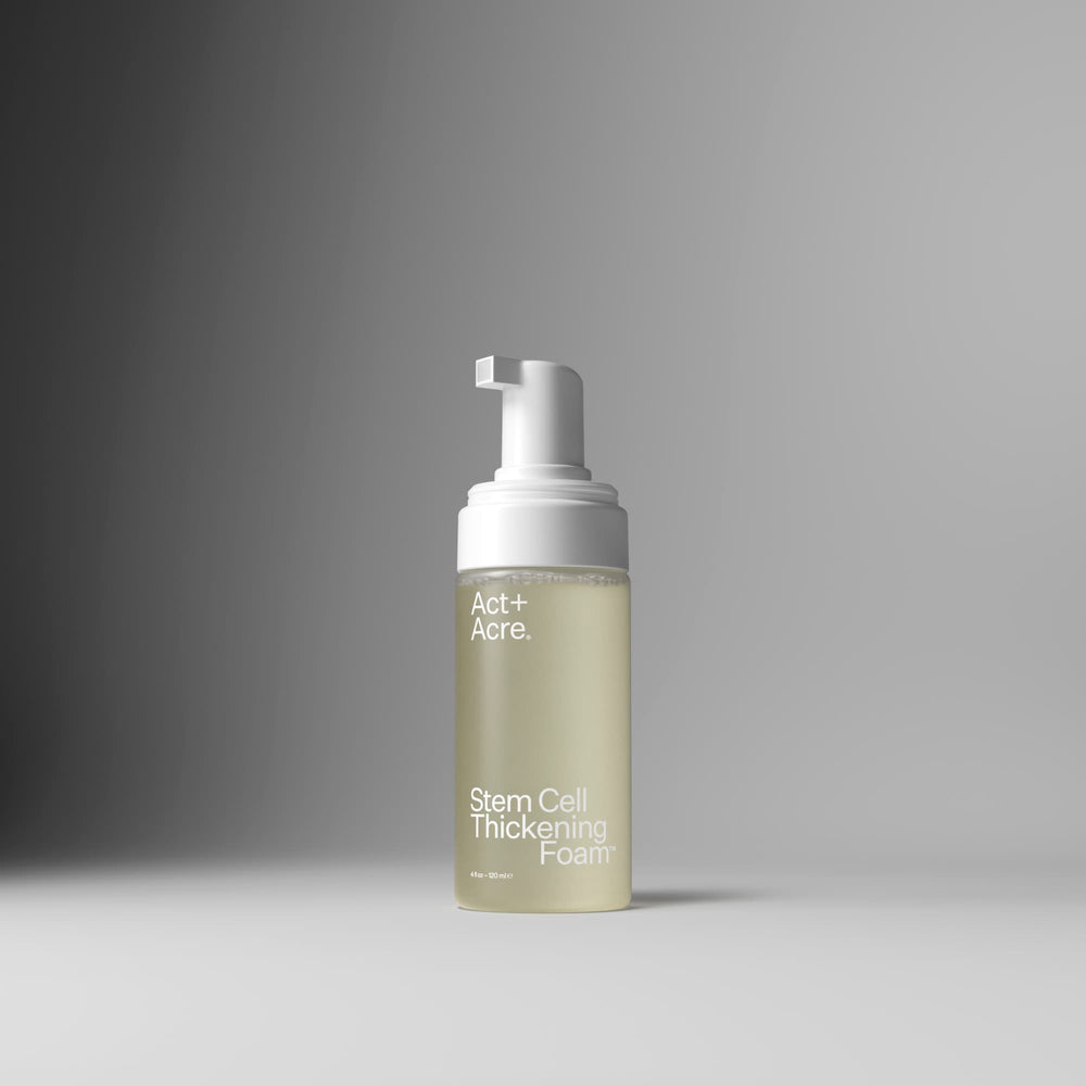 A bottle of Act+A. Stem Cell Thickening Foam with a white pump dispenser and a frosted clear bottle showing a pale yellow-green liquid, set against a clean gray gradient background.