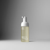 A bottle of Act+A. Stem Cell Thickening Foam with a white pump dispenser and a frosted clear bottle showing a pale yellow-green liquid, set against a clean gray gradient background.