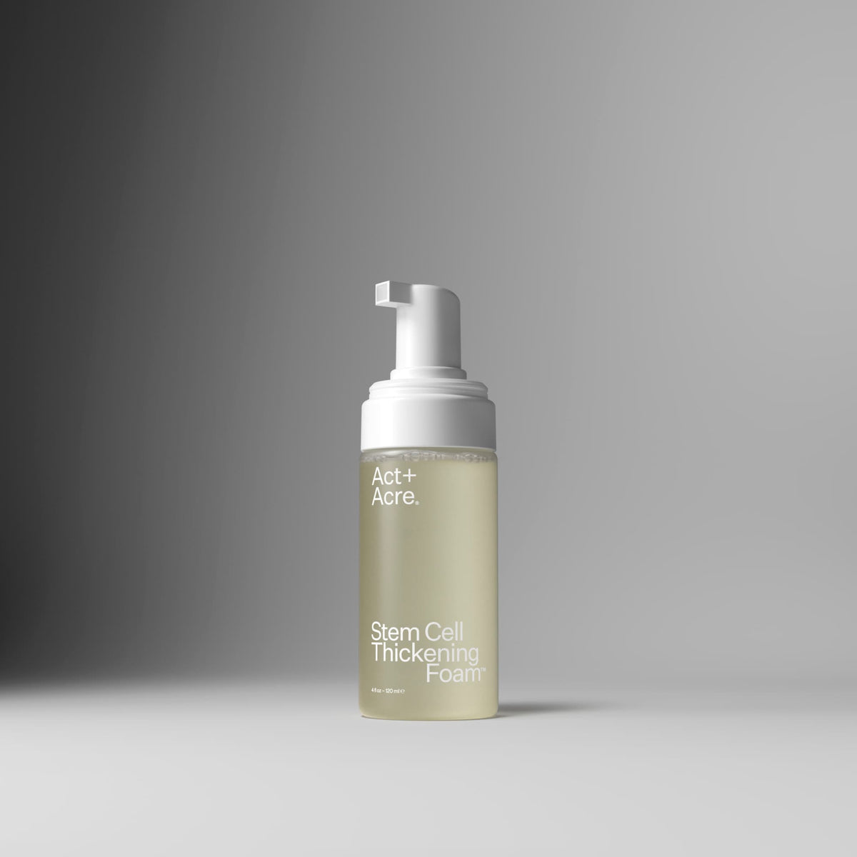 A bottle of Act+A. Stem Cell Thickening Foam with a white pump dispenser and a frosted clear bottle showing a pale yellow-green liquid, set against a clean gray gradient background.