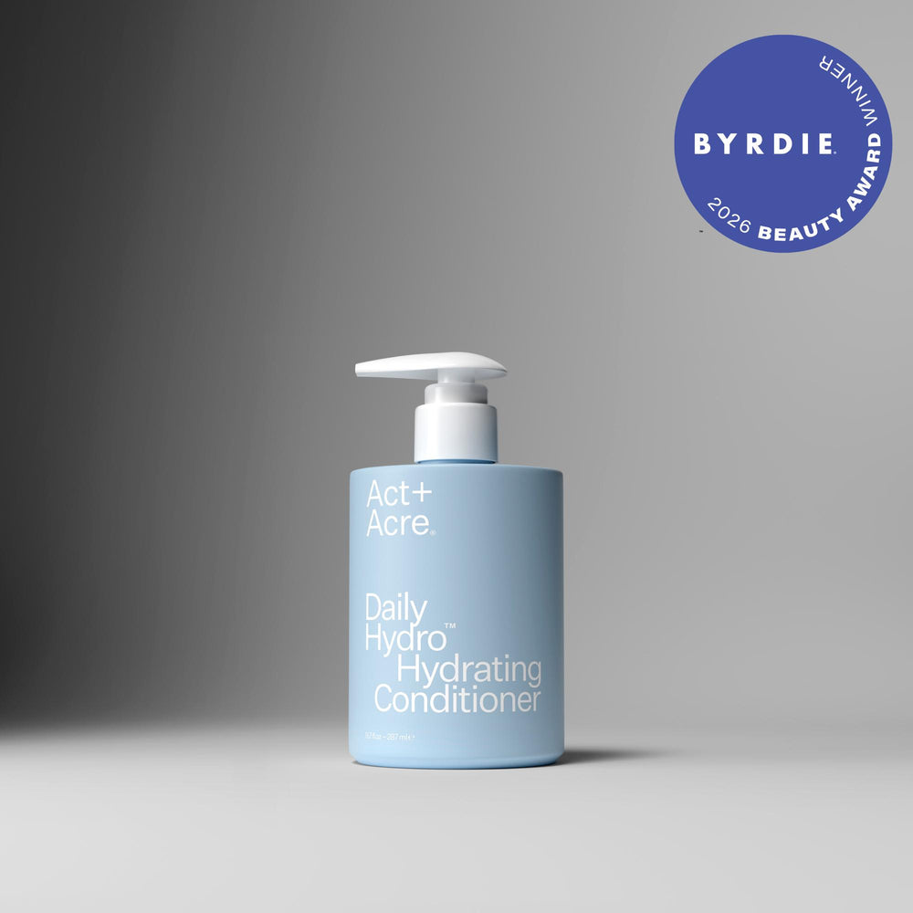 A bottle of Act+ Acre. Daily Hydro Hydrating Conditioner in a light blue bottle with a white pump dispenser, set against a dark-to-light gray gradient background.