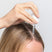Person with blonde hair applying Act+Acre Stem Cell Scalp Serum